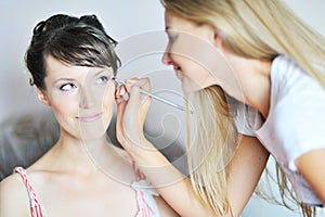 Young beautiful bride applying wedding make-up