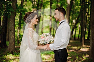 Young and beautiful bride and bridegroom holding one another hands