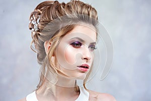 Young beautiful bride with an elegant high hairdo. Wedding hairstyle with the accessory in her hair