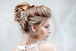 Young beautiful bride with an elegant high hairdo. Wedding hairstyle with the accessory in her hair