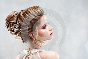 Young beautiful bride with an elegant high hairdo. Wedding hairstyle with the accessory in her hair