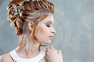 Young beautiful bride with an elegant high hairdo. Wedding hairstyle with the accessory in her hair