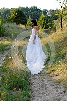 Young beautiful bride on green lawn passage