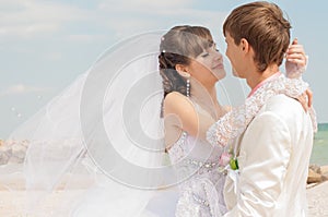 Young and beautiful bride and groom on the beach