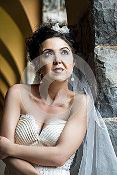 Young beautiful bride leaning against rock wall