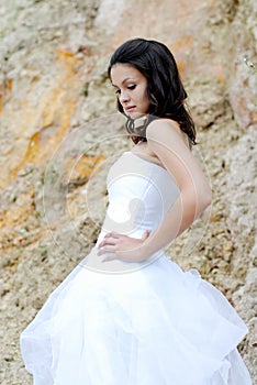 Young beautiful bride among rocks outdoors