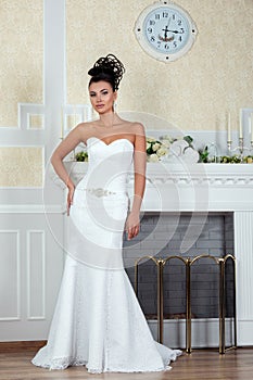 Young beautiful bride standing near fireplace