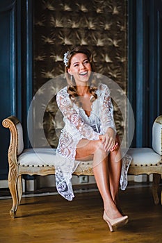 Young beautiful bride in white negligee preparing to wedding ceremony