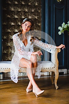 Young beautiful bride in white negligee preparing to wedding ceremony