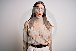 Young beautiful brunette businesswoman wearing casual sweater and glasses standing afraid and shocked with surprise expression,