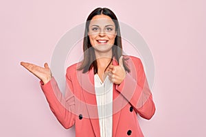 Young beautiful brunette businesswoman wearing elegant jacket over isolated pink background Showing palm hand and doing ok gesture