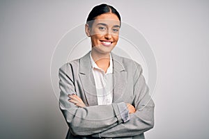 Young beautiful brunette businesswoman wearing jacket standing over white background happy face smiling with crossed arms looking