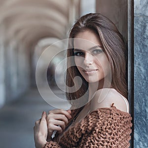 Young beautiful brunette in fashionable clothes near the wall