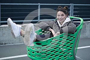 Young beautiful brunette girl in a cart in the Parking lot of a shopping center, having fun and having a good time, fooling around