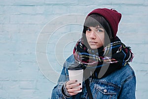 Young beautiful brunette girl drinking coffee on a cold street
