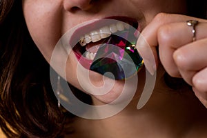 Young beautiful brunette girl with the gemstone in her mouth