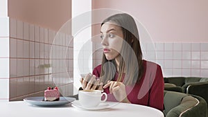 Young beautiful brunette girl smiling sitting in cafe, using smartphone, texting, looking away 60 fps