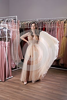 Young beautiful brunette girl wearing a full-length beige yellow champaign chiffon slit prom ball gown decorated with