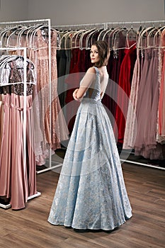 Young beautiful brunette girl wearing a full-length draped sky blue satin slit prom ball gown decorated with