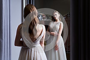 Young beautiful brunette girl wearing a full-length silver white chiffon prom ball gown decorated with sparkles and