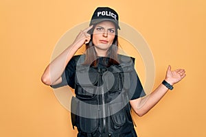 Young beautiful brunette policewoman wearing police uniform bulletproof and cap confused and annoyed with open palm showing copy