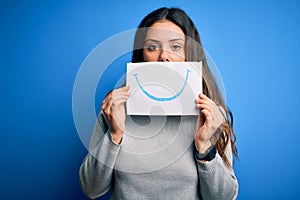 Young beautiful brunette positive woman holding card with smile emotion on mouth with a confident expression on smart face