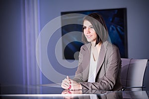 Young beautiful brunette television announcer at studio during live broadcasting.Female TV director at editor in studio.