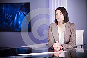 Young beautiful brunette television announcer at studio during live broadcasting.Female TV director at editor in studio.