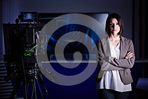 Young beautiful brunette television announcer at studio during live broadcasting.Female TV director at editor in studio.