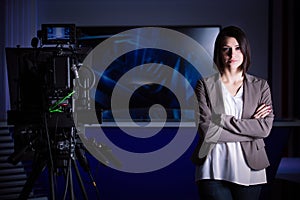 Young beautiful brunette television announcer at studio during live broadcasting.Female TV director at editor in studio. photo