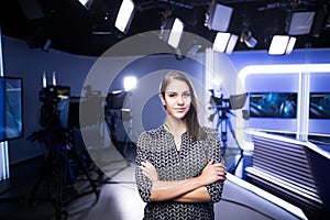 Young beautiful brunette television announcer at studio standing next to the camera.TV director at editor in studio