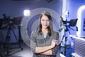 Young beautiful brunette television announcer at studio standing next to the camera. TV director at editor in studio