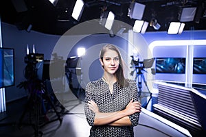 Young beautiful brunette television announcer at studio standing next to the camera.TV director at editor in studio photo