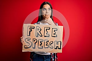 Young beautiful brunette woman asking for rights holding banner with free speech message serious face thinking about question,