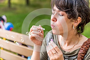 Young beautiful brunette woman blowing soap bubbles outdoor