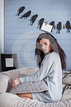 Young beautiful brunette woman with cup of coffee sitting home o