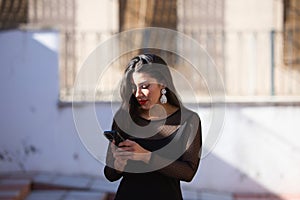 Young, beautiful brunette woman is dressed elegantly in a black dress with transparencies and fancy earrings. The girl is walking photo