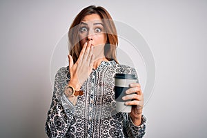 Young beautiful brunette woman drinking glass of takeaway coffe over white background cover mouth with hand shocked with shame for