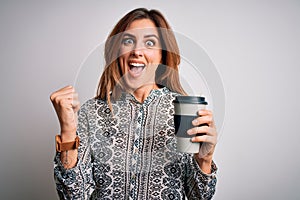 Young beautiful brunette woman drinking glass of takeaway coffe over white background screaming proud and celebrating victory and