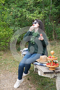 young beautiful brunette woman eat strawberry dessert at picnic on the bench