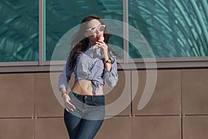 Young, beautiful brunette woman eating a pink ice cream in a waffle horn. She`s in a good mood She wears glasses with dark glasse