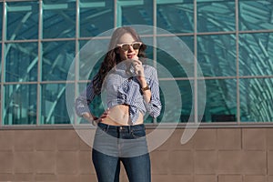 Young, beautiful brunette woman eating a pink ice cream in a waffle horn. She`s in a good mood She wears glasses with dark glasse