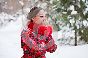 Young beautiful brunette woman in fur coat posing on winter park
