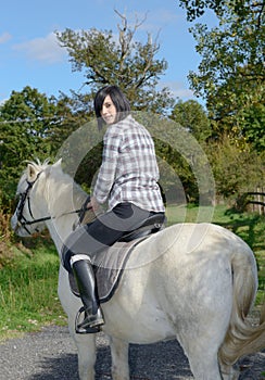 Young beautiful brunette woman riding horse