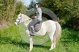 Young beautiful brunette woman riding horse