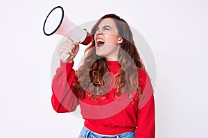 Young beautiful brunette woman screaming using megaphone over isolated white background