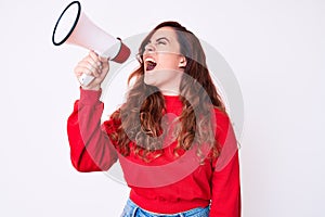 Young beautiful brunette woman screaming using megaphone over isolated white background