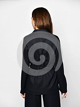 Young beautiful brunette woman in stylish pantsuit pajama is posing backwards over grey background