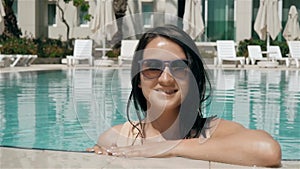 Young Beautiful Brunette Woman In Sunglasses Enjoys Water In Swimming Pool