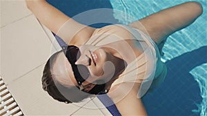 Young Beautiful Brunette Woman In Sunglasses Enjoys Water In Swimming Pool